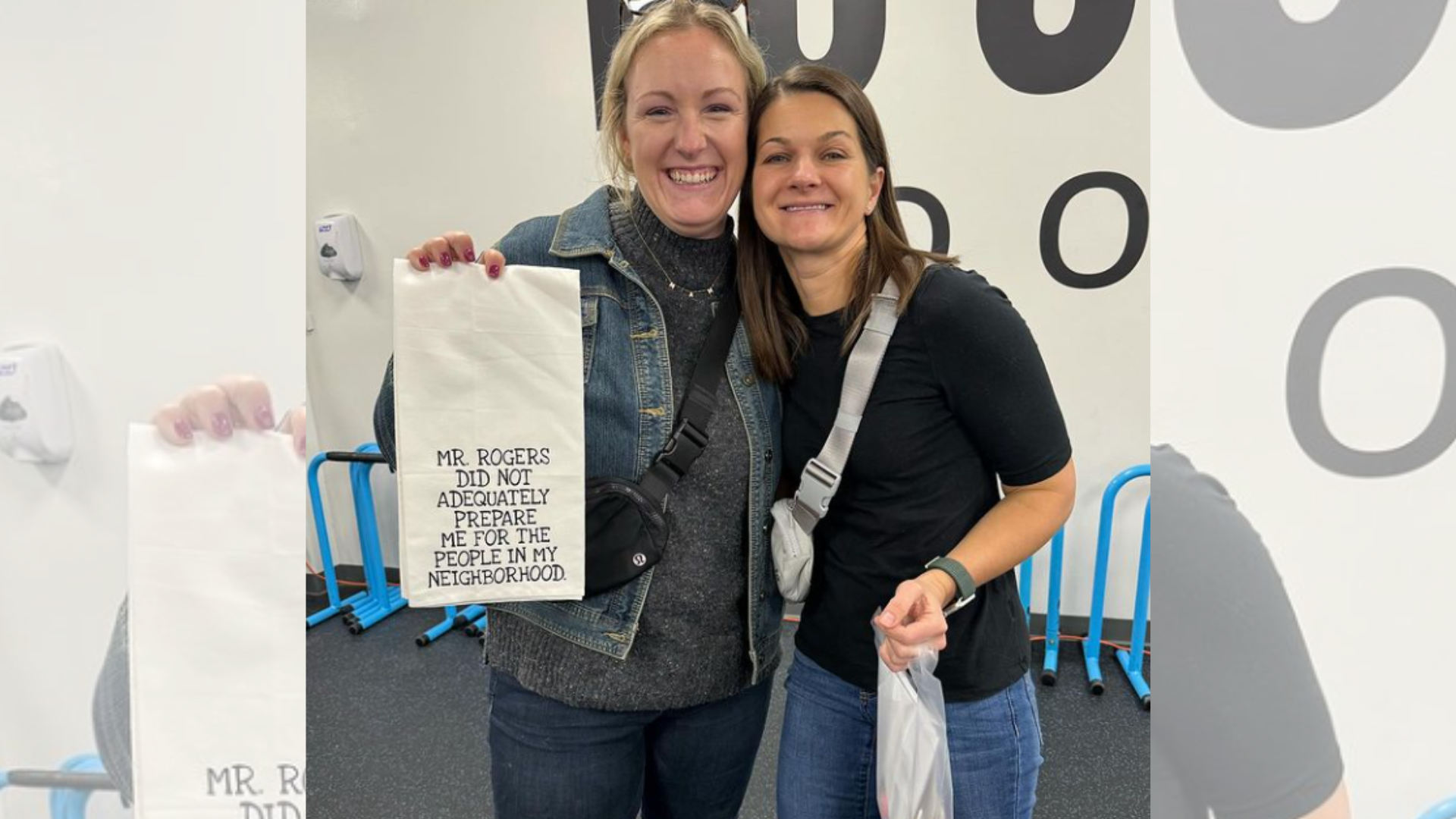 Two women are standing next to each other holding a bag.