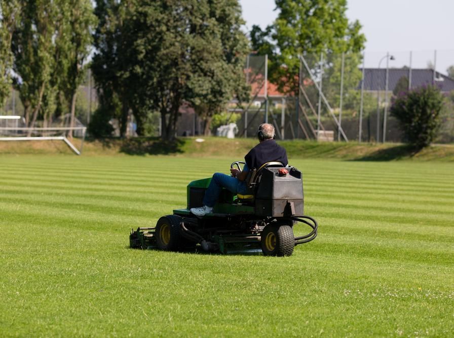 A Man is Riding a Lawn Mower on a Lush Green Field — 4WD Slashing & Large Area Mowing In Alstonville, NSW