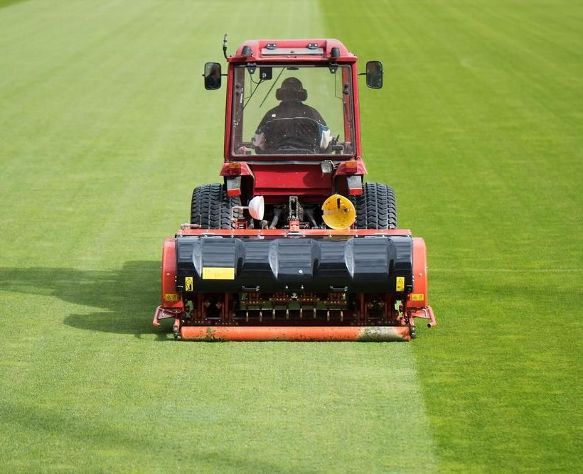 A Red Tractor is Cutting Grass on a Lush Green Field — 4WD Slashing & Large Area Mowing In Evans Head, NSW