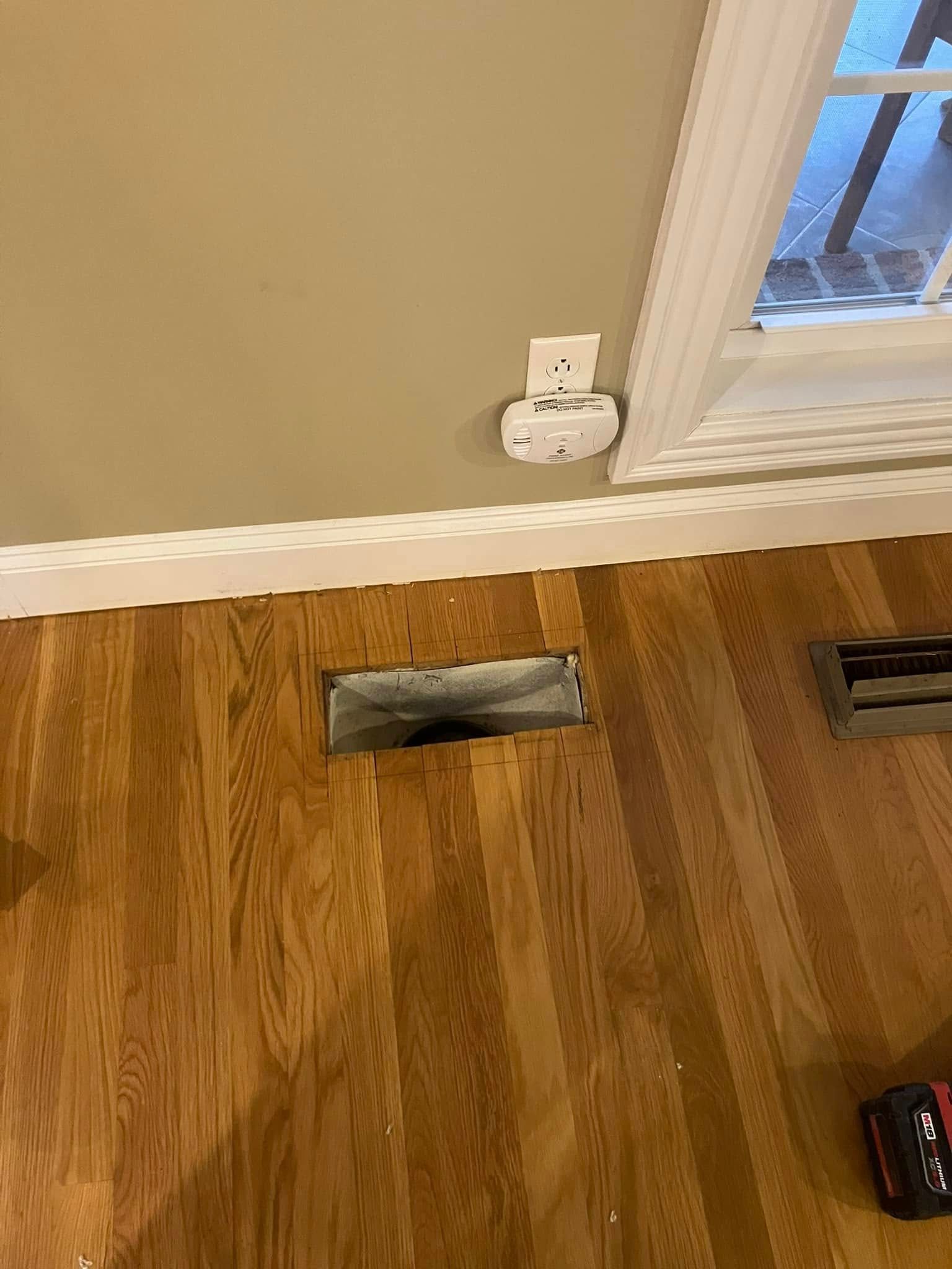 A hole in the floor in a living room next to a window.