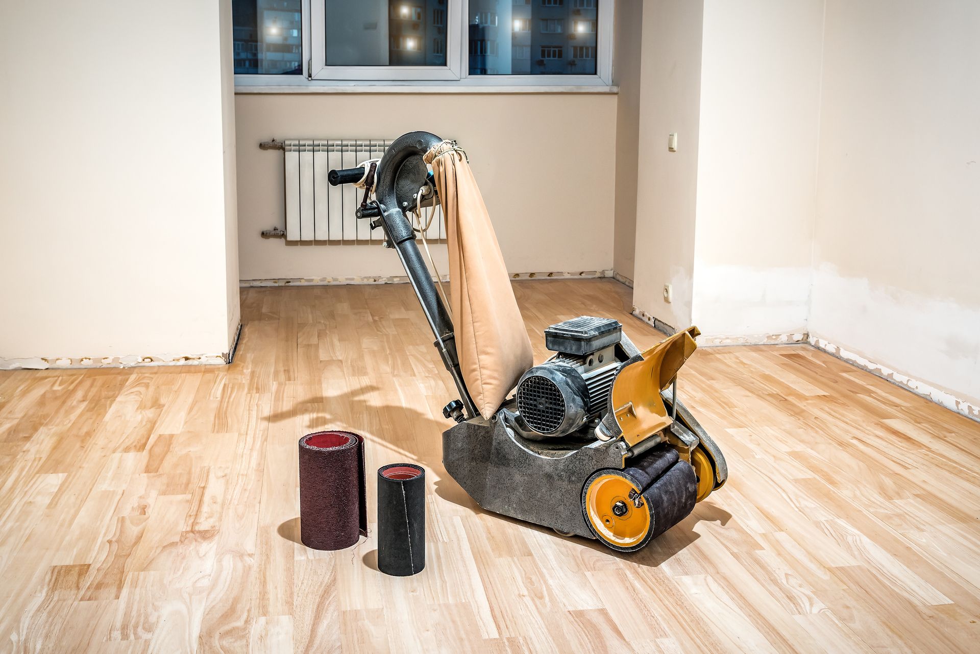A machine is sitting on a wooden floor in an empty room.
