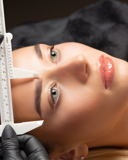 Eine Frau misst ihre Augenbrauen mit einem Lineal.