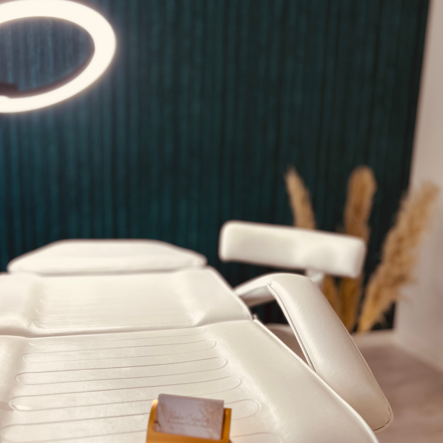 In einem Raum steht ein weißer Stuhl mit einem Ringlicht darüber.