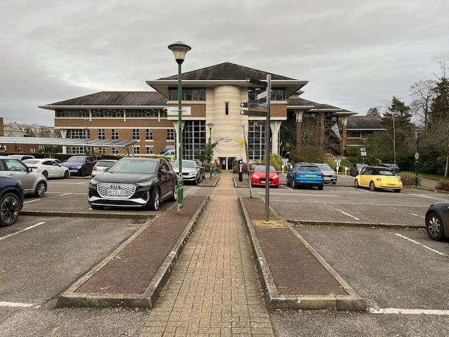 A parking lot with cars parked in front of a large building.