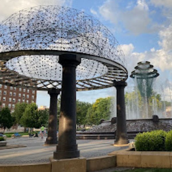 A fountain in a park with a dome sculpture in the foreground.