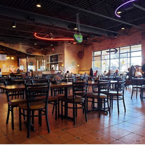 A restaurant filled with tables and chairs and a neon sign