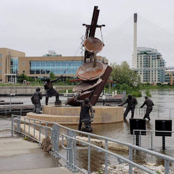 A group of statues standing next to a body of water