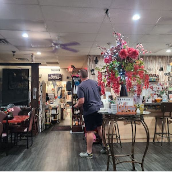A man standing in a restaurant with flowers on a table