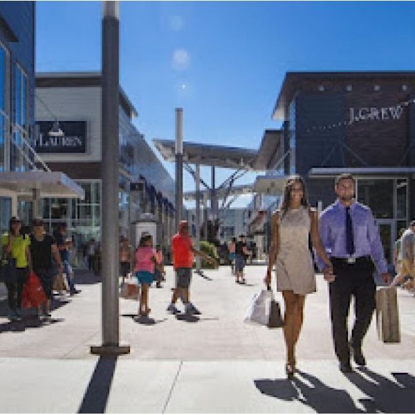 A man and woman are walking down a sidewalk in front of a j.crew store
