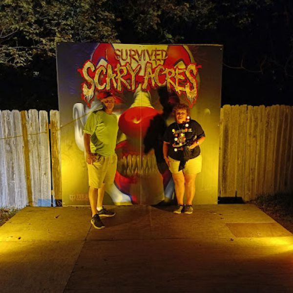 Two people standing in front of a sign that says scary acres