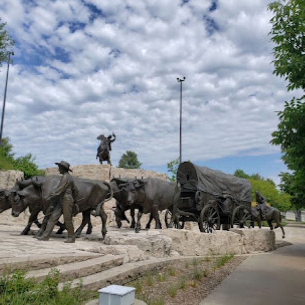 A statue of a wagon being pulled by a herd of cows