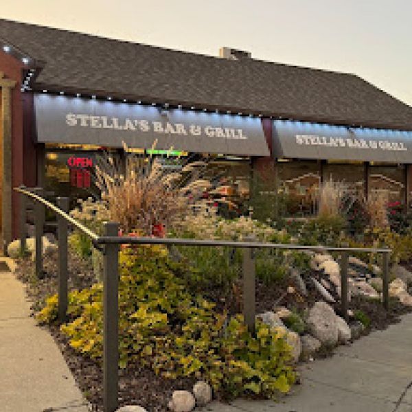 A restaurant called stella 's bar and grill is surrounded by plants and rocks.