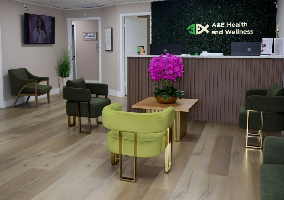 Modern clinic waiting room with green chairs, wood flooring, reception desk, and pink flowers