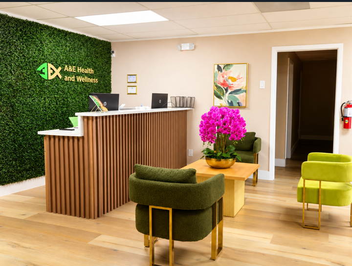Modern office reception area with wood counter, green chairs, and a bright pink flower arrangement