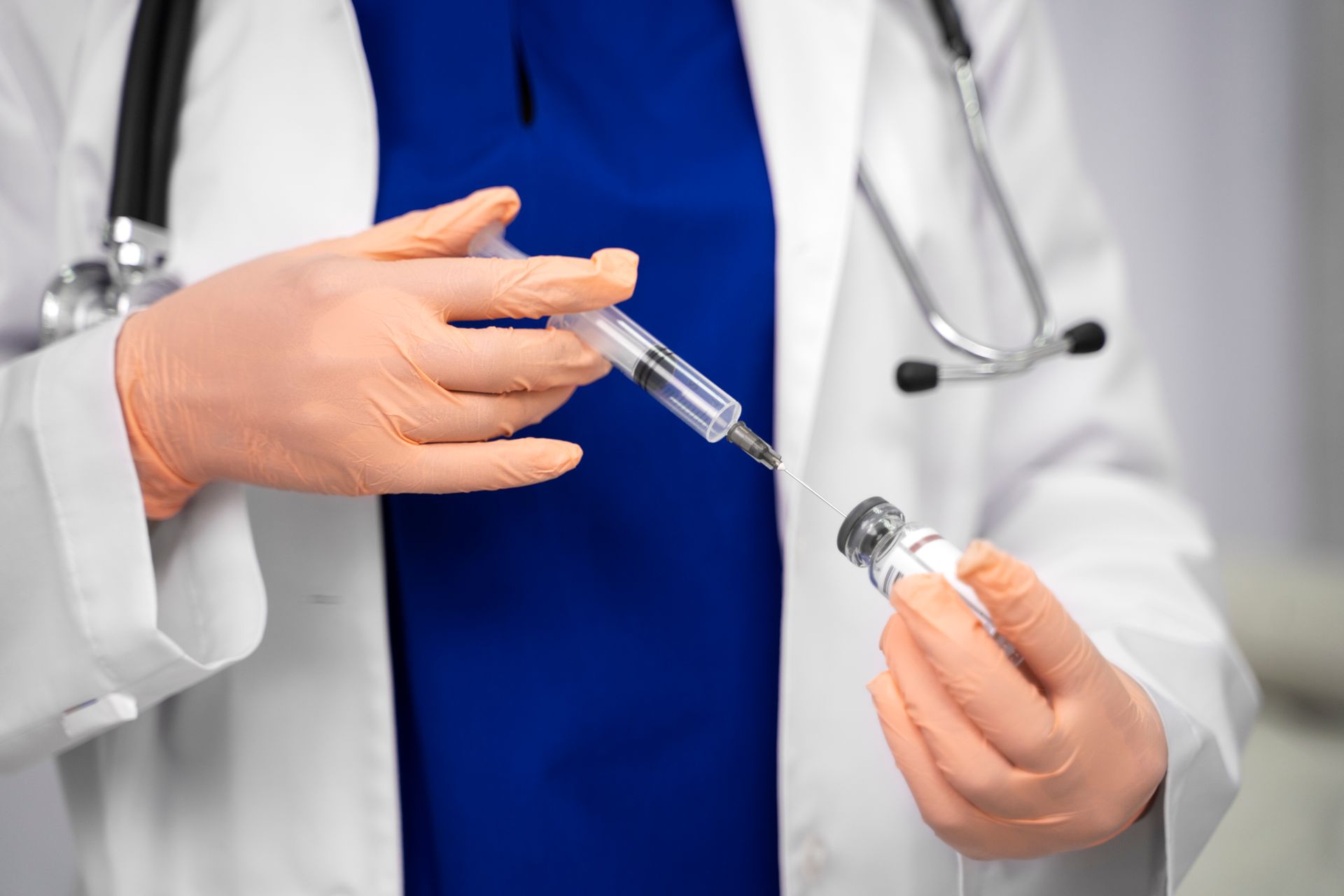 Doctor holding a syringe and vial in a clinical setting