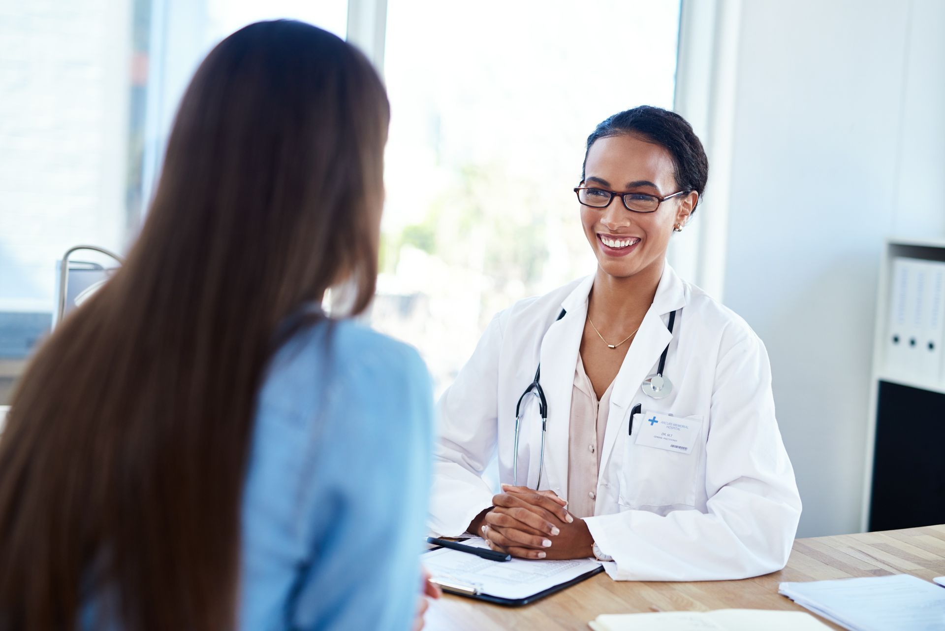 Doctor smiling during consultation with a patient across a desk in a bright office