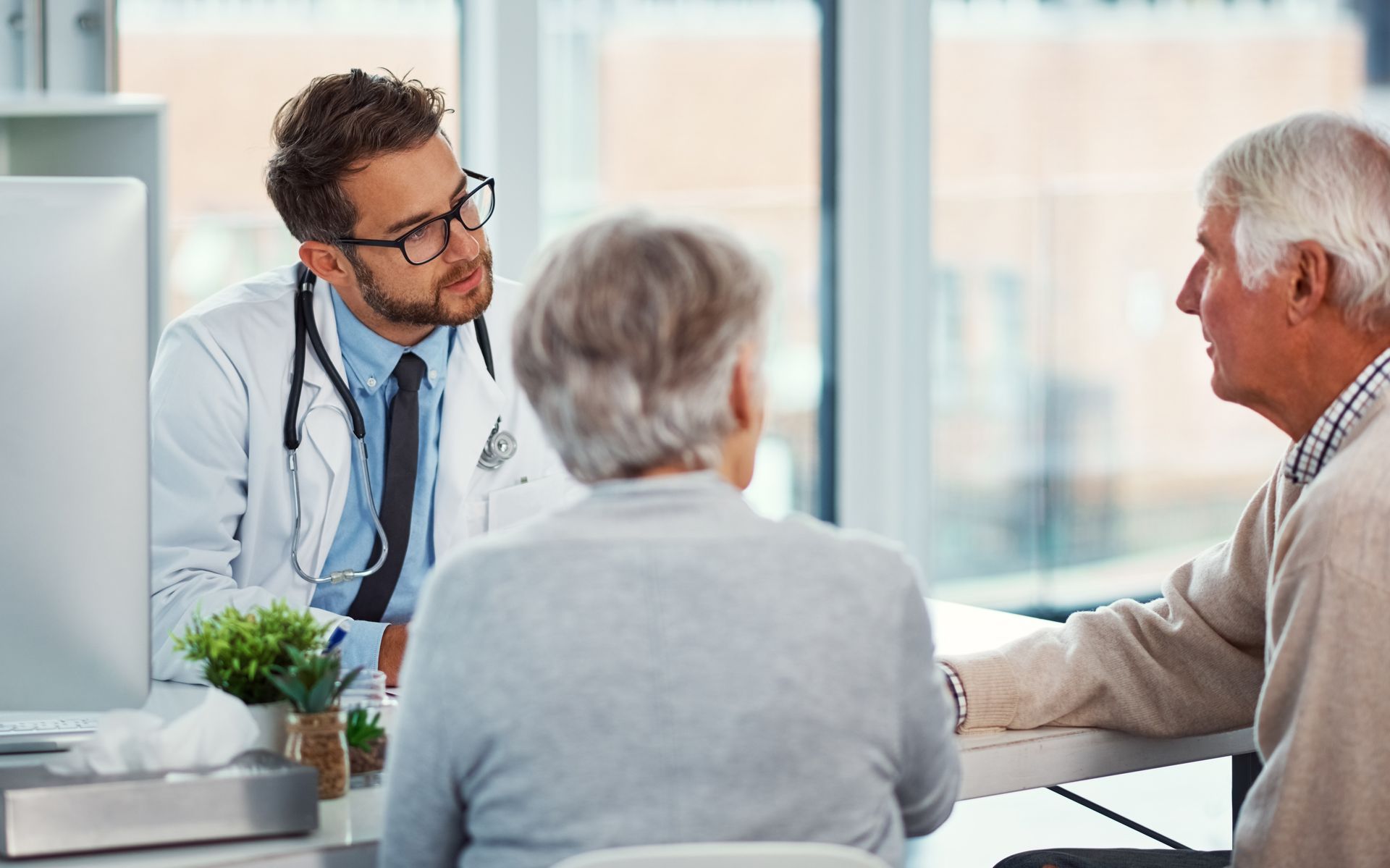 Doctor consulting with two patients in a bright office