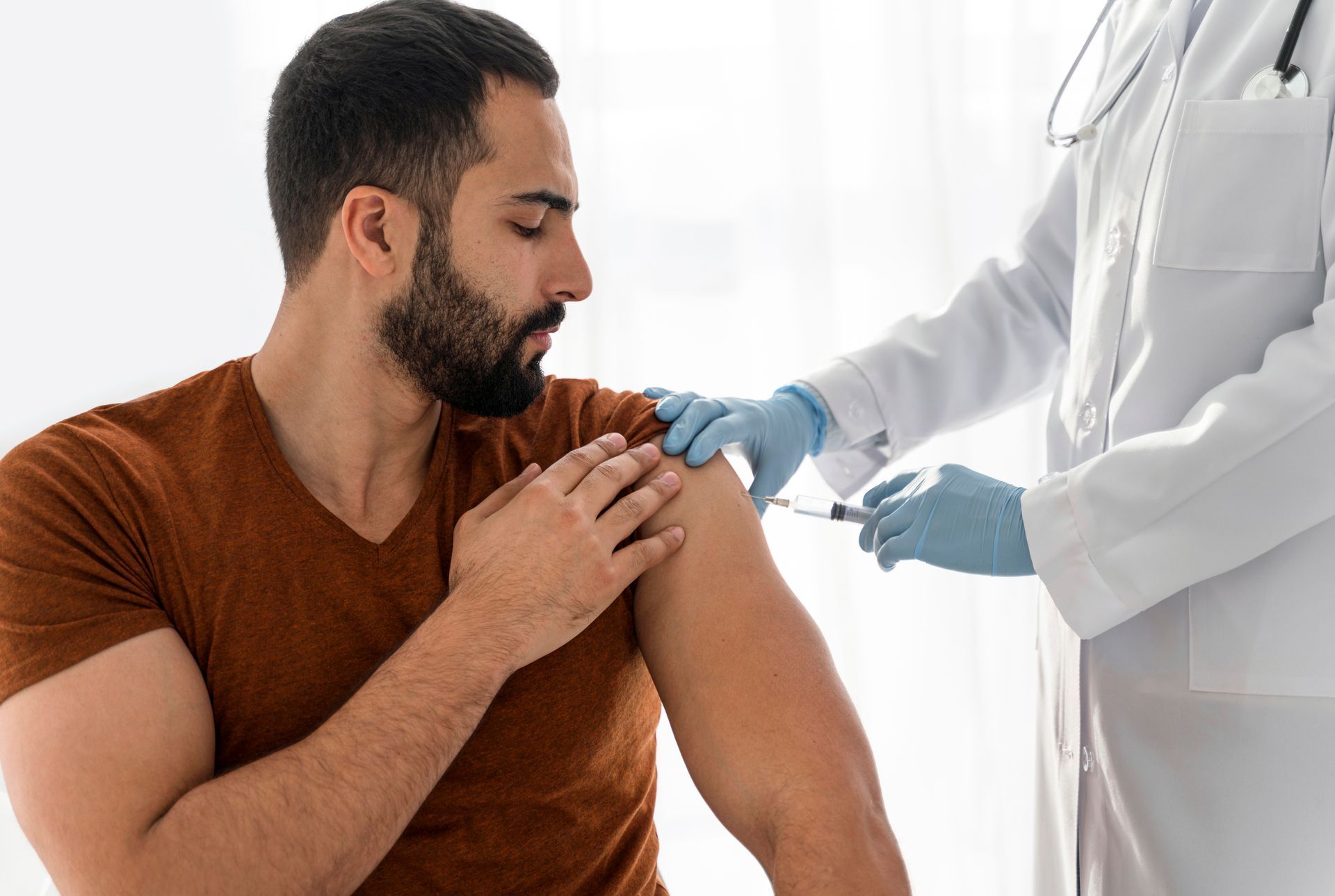 Patient receiving a vaccine injection in the upper arm from a healthcare worker