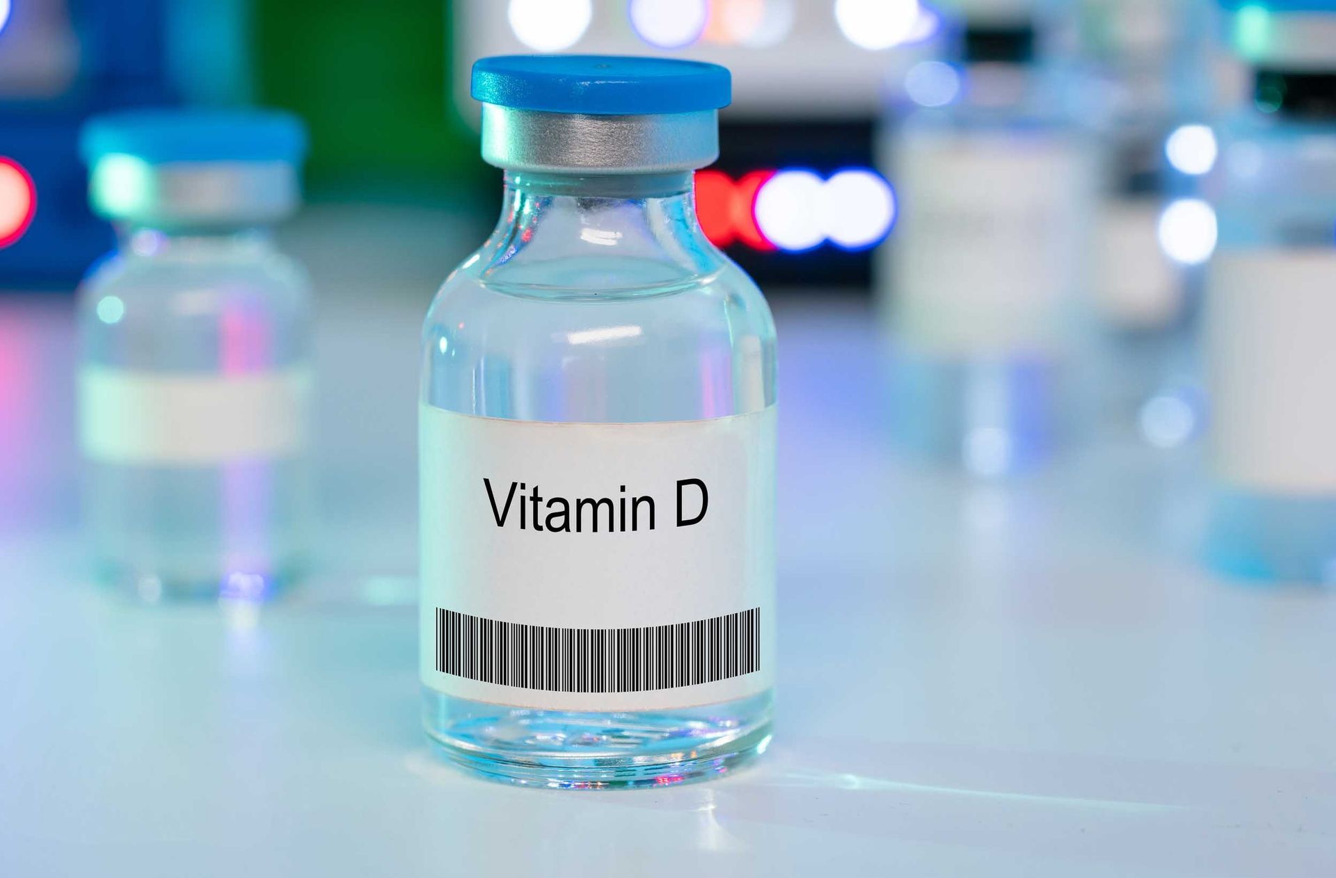 Vitamin D bottle with barcode label on a laboratory counter, with blurred vials in the background