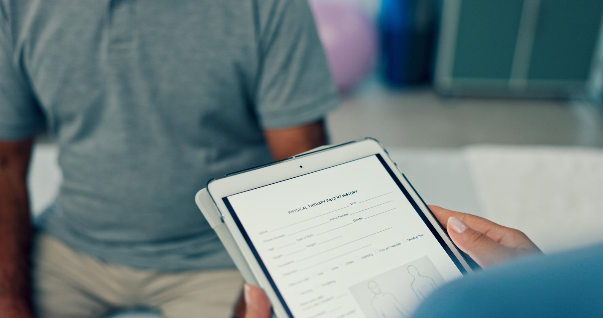Tablet showing a checklist held by a person in a gray shirt during a consultation.
