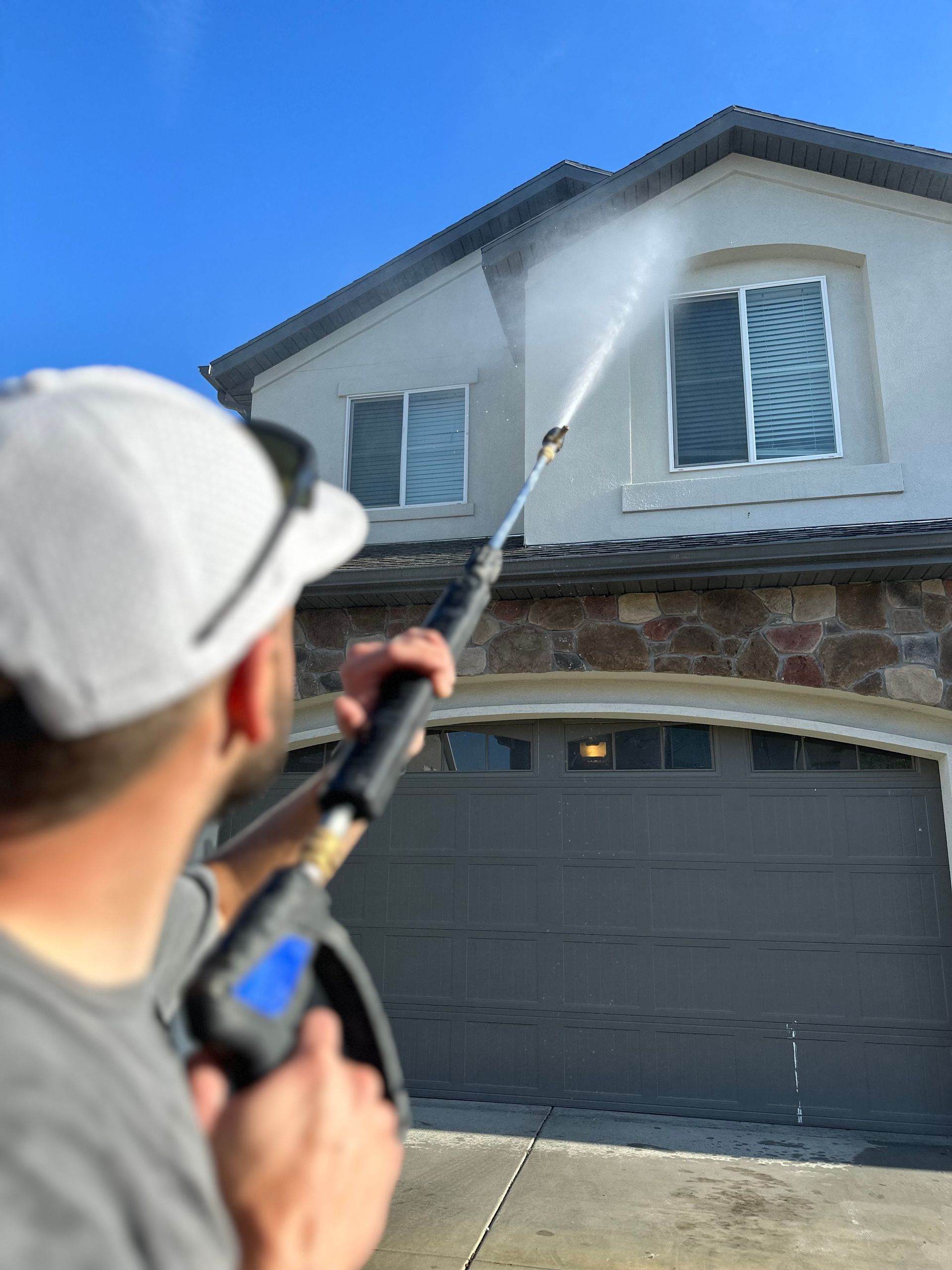 A man wearing a white hat and shirt sprays paint on a house, representing the Satisfy Utah campaign.