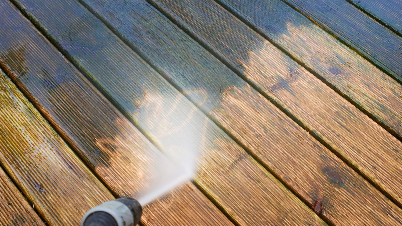 A pressure washer is actively cleaning a wooden deck, showcasing the effectiveness of the cleaning process.