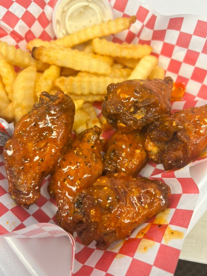 A basket of chicken wings and french fries on a checkered paper