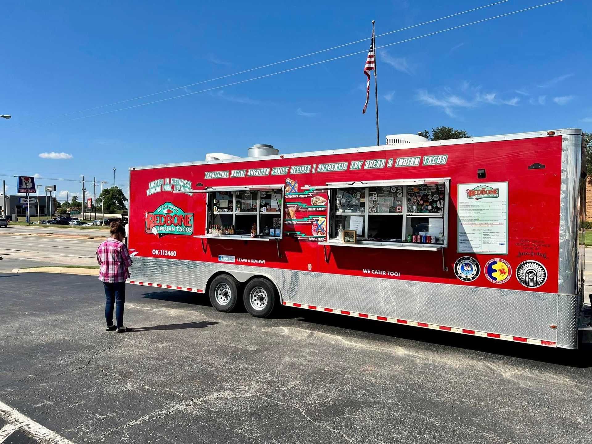 A red and silver food truck is parked in a parking lot.