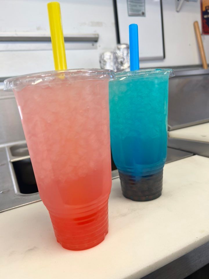 Two cups of drinks with straws in them on a counter
