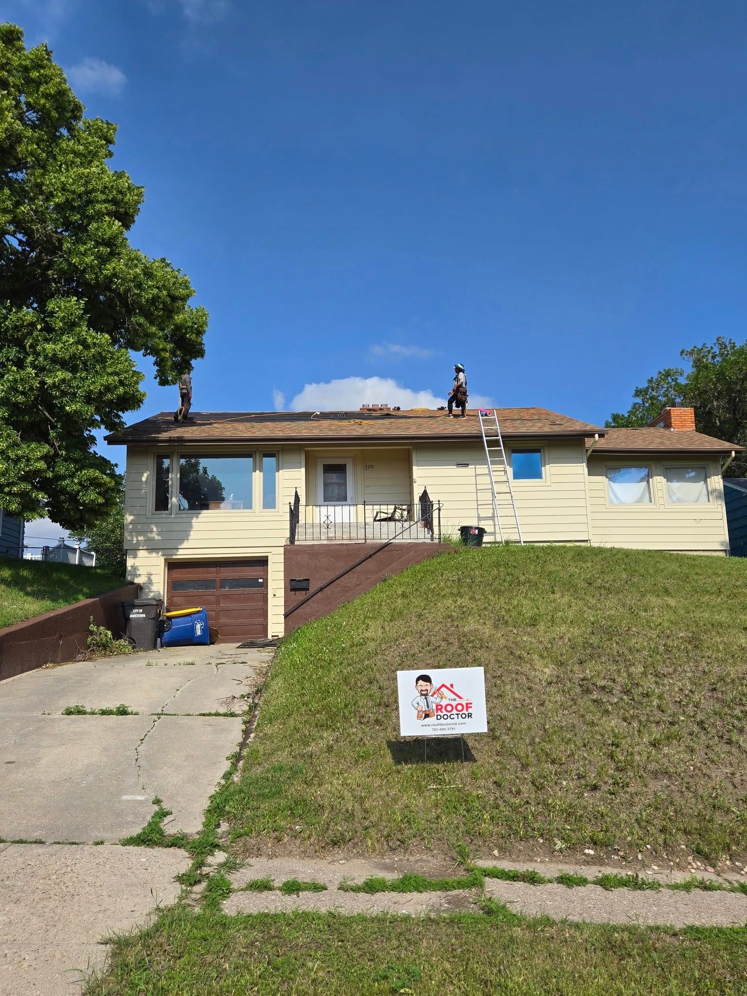 A house with a sign on the grass in front of it.