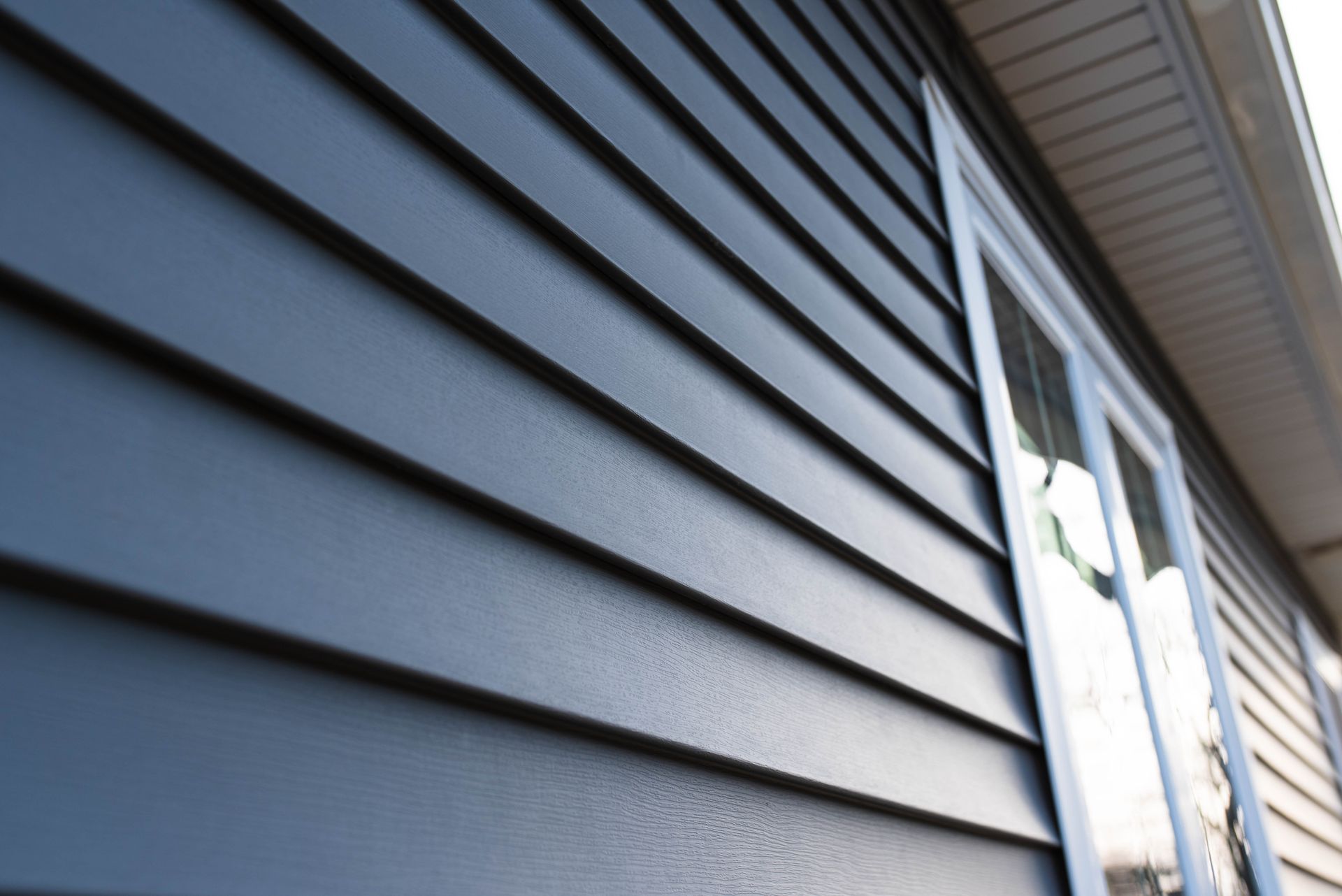 Blue siding on a house with a white framed window.