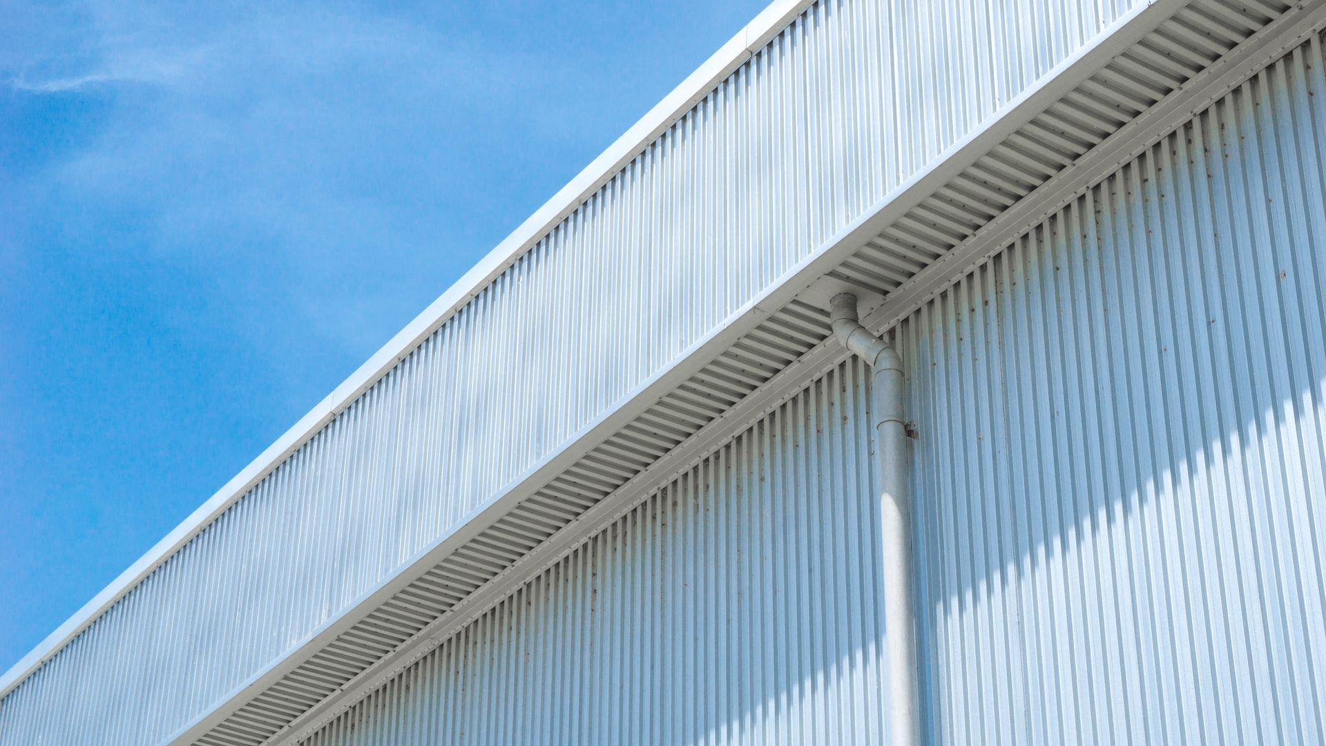 Exterior of a building with corrugated metal siding, light blue sky in background.