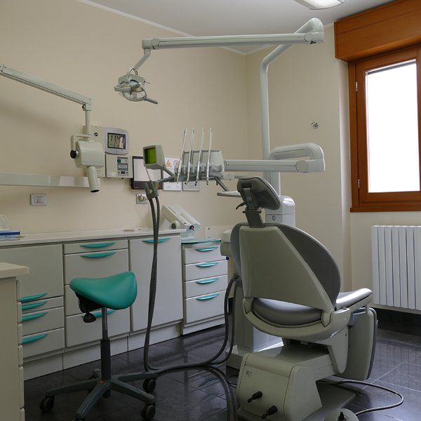 Uno studio dentistico con una sedia grigia e uno sgabello verde