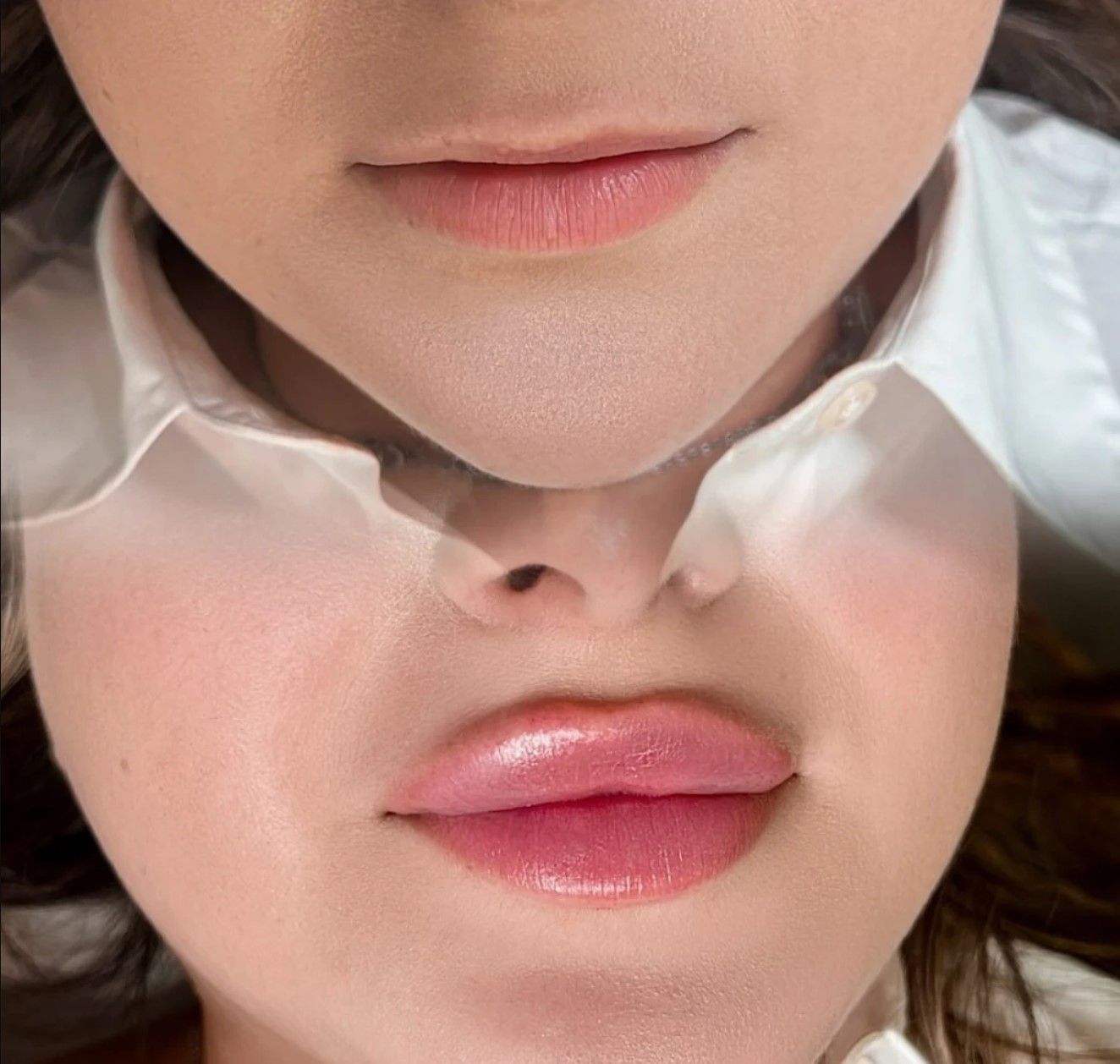 A close up of a woman 's face with pink lips and a white shirt.