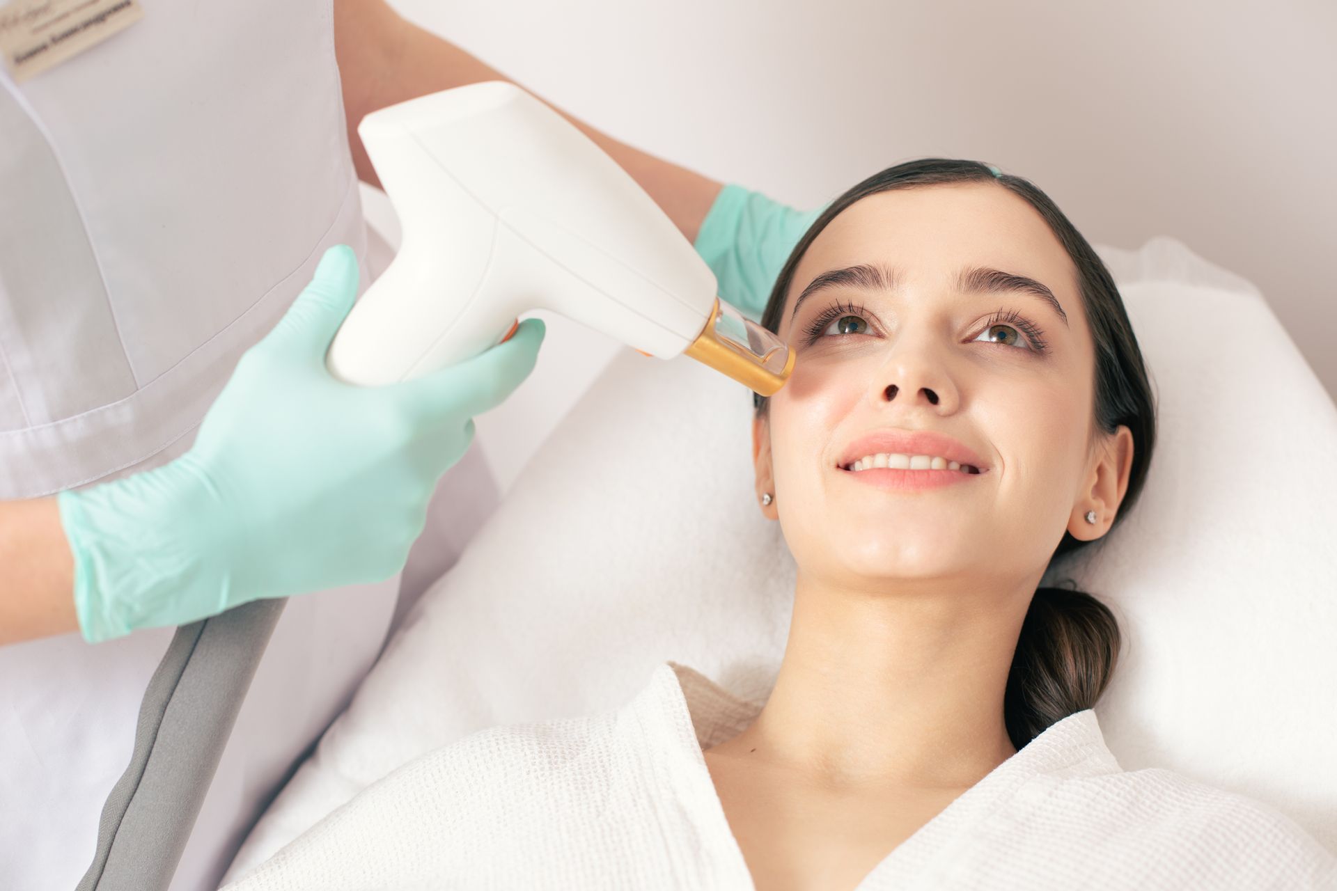Woman receiving laser skin treatment on her face by a gloved medical professional.