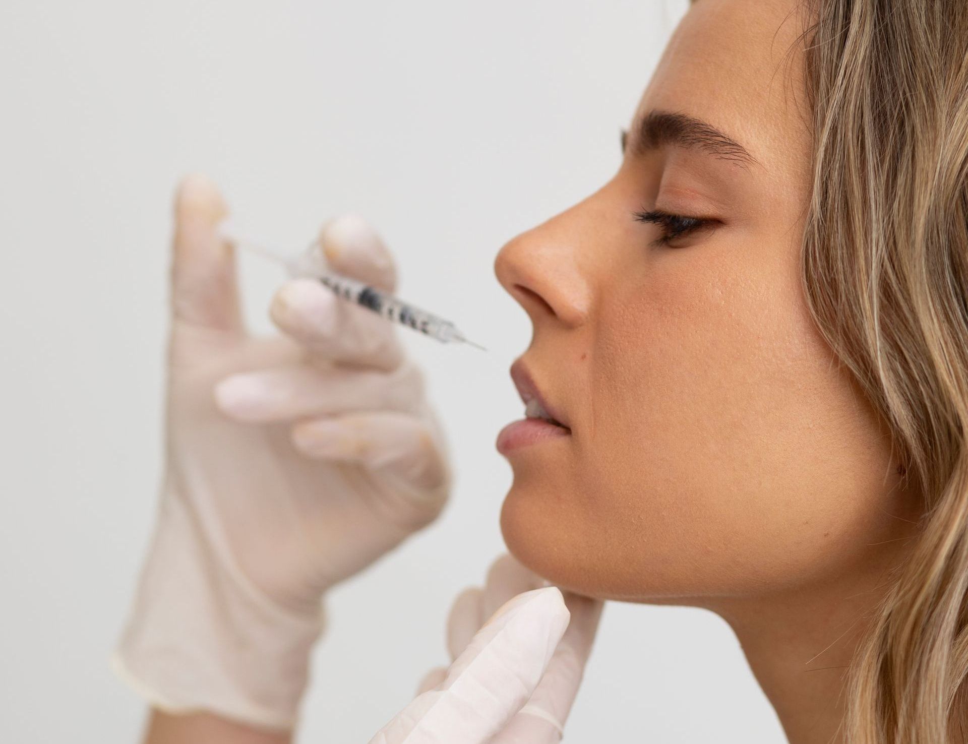 A woman is applying lip gloss to her lips with a brush.