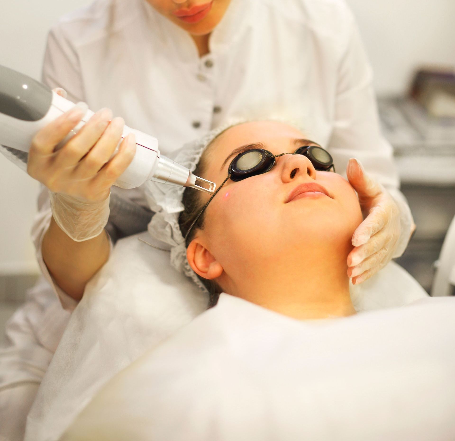 A woman wearing goggles is getting a laser treatment on her face
