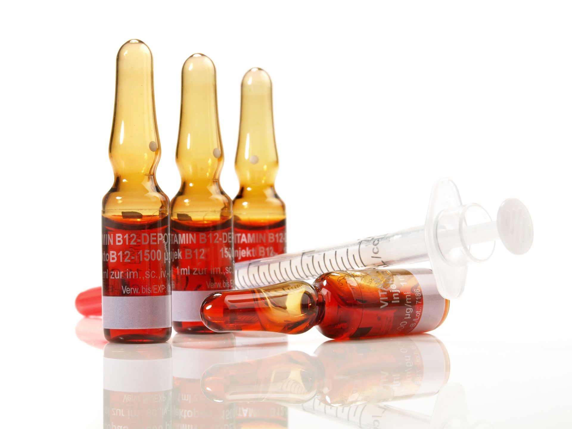 A syringe is sitting next to a group of ampoules