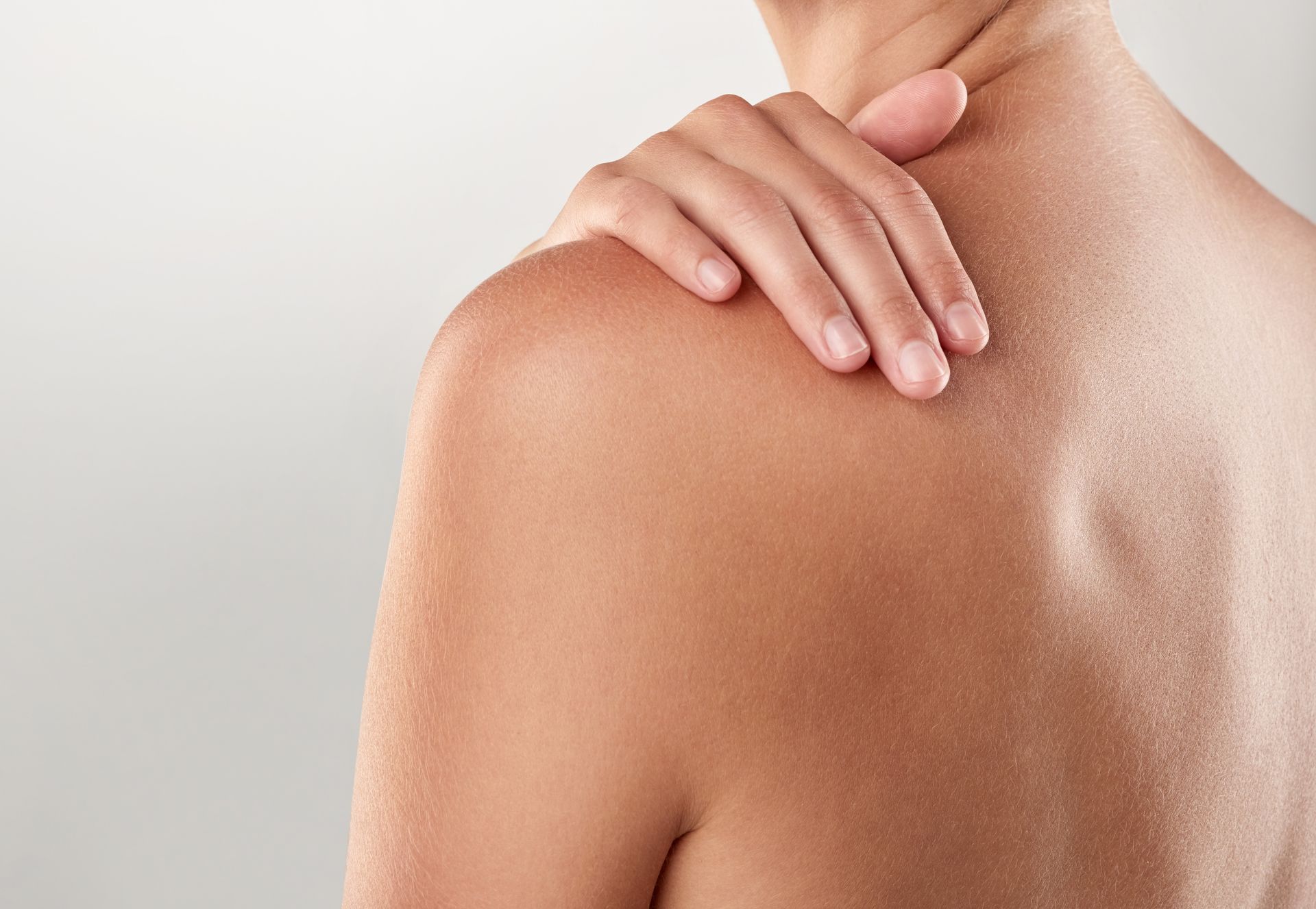 A woman is holding her shoulder in pain.