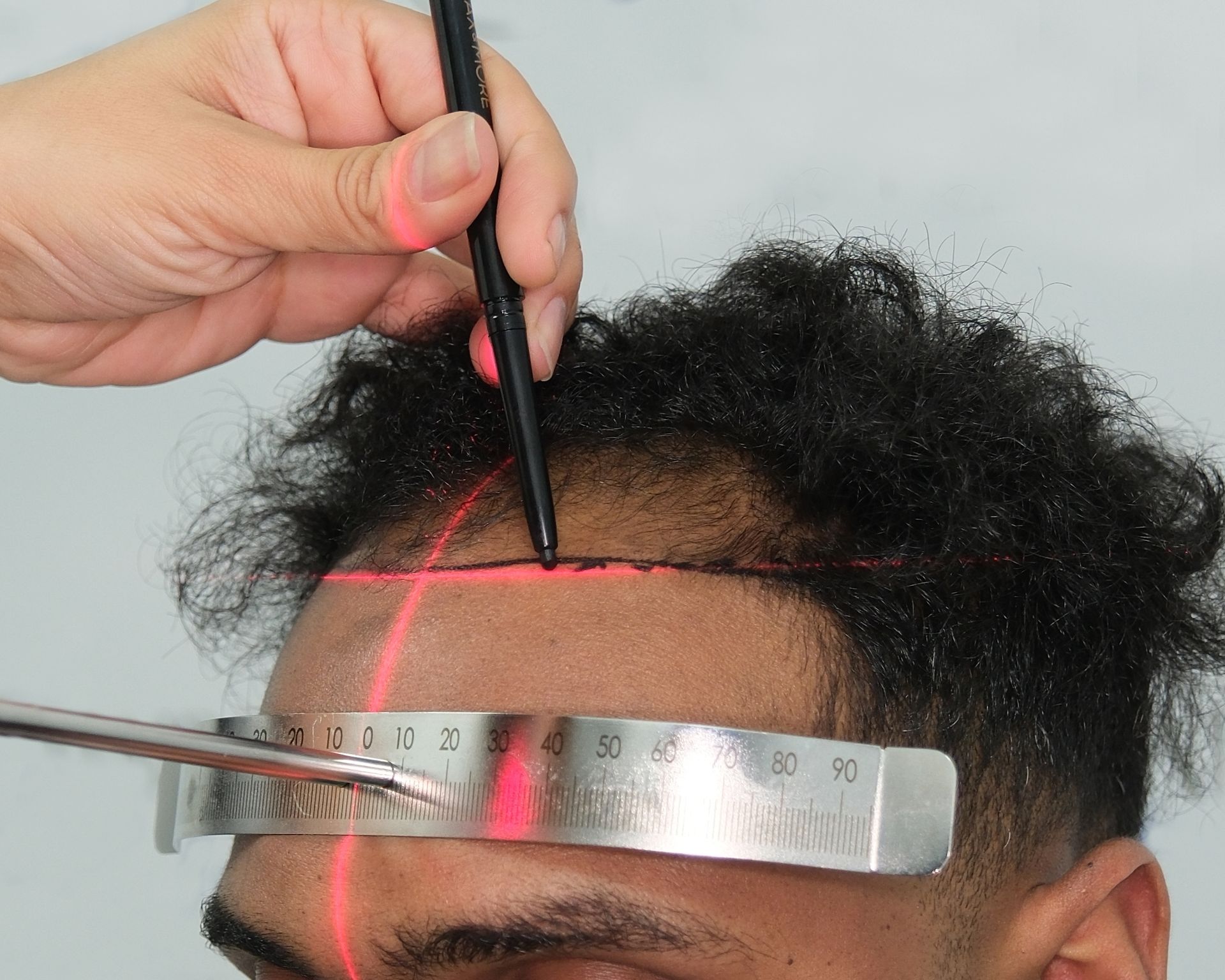 A man is being measured with a ruler and a pen