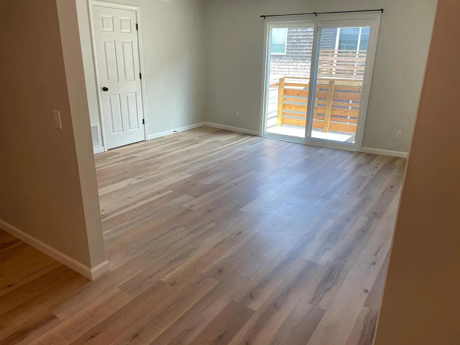A living room with hardwood floors and a sliding glass door.