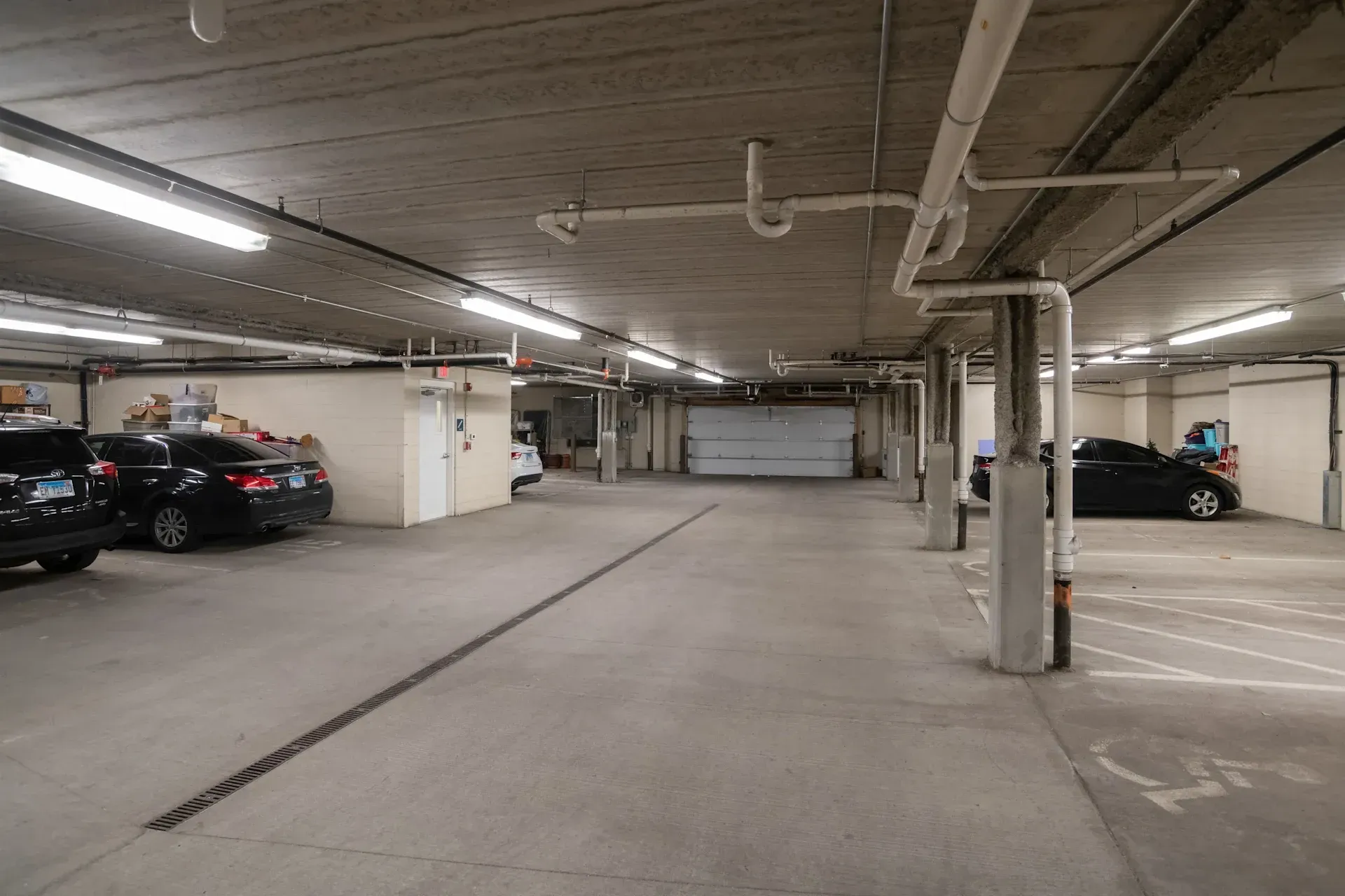 A parking garage with cars parked in it and a garage door.