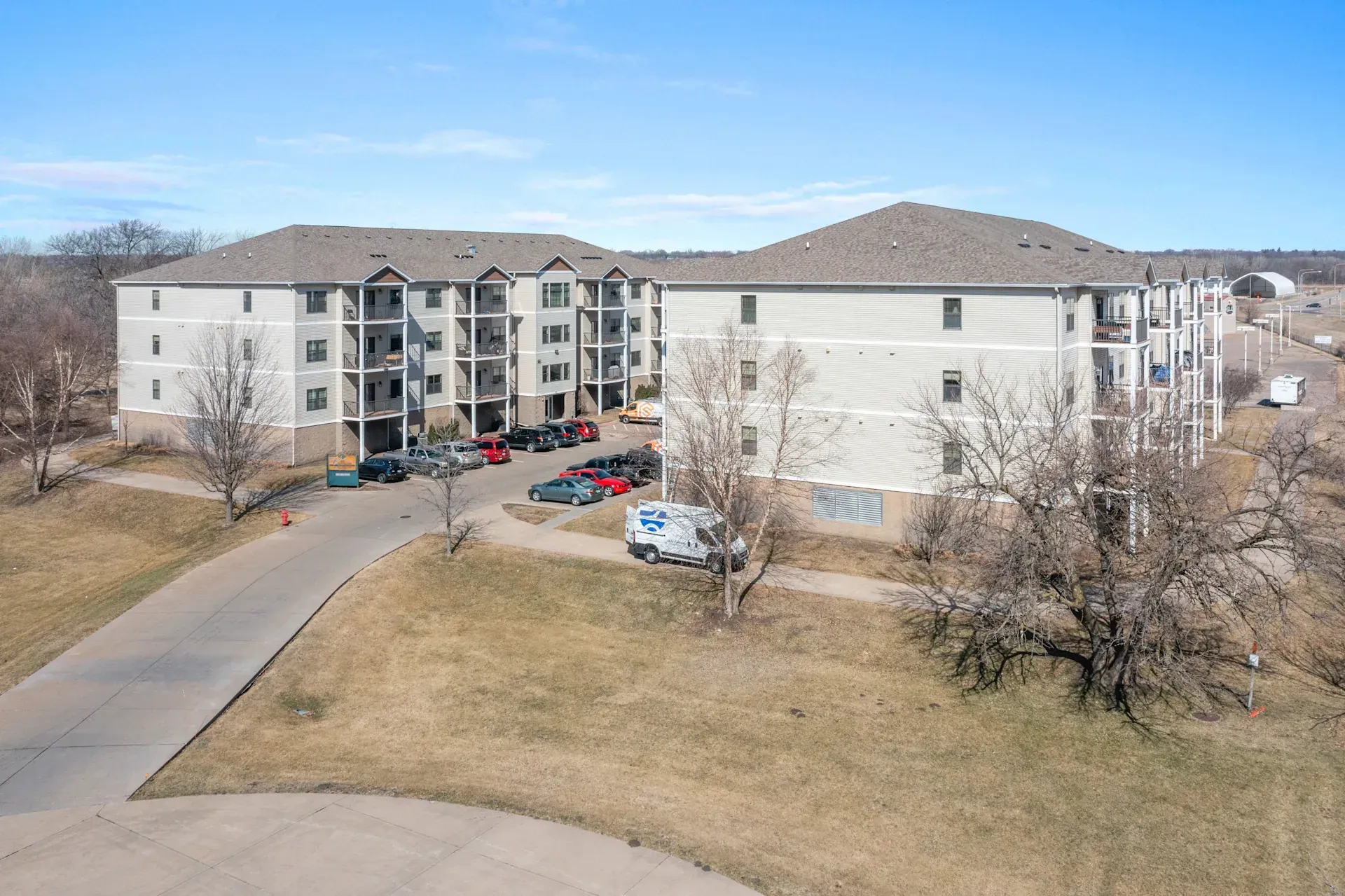 An aerial view of a large apartment building with cars parked in front of it.