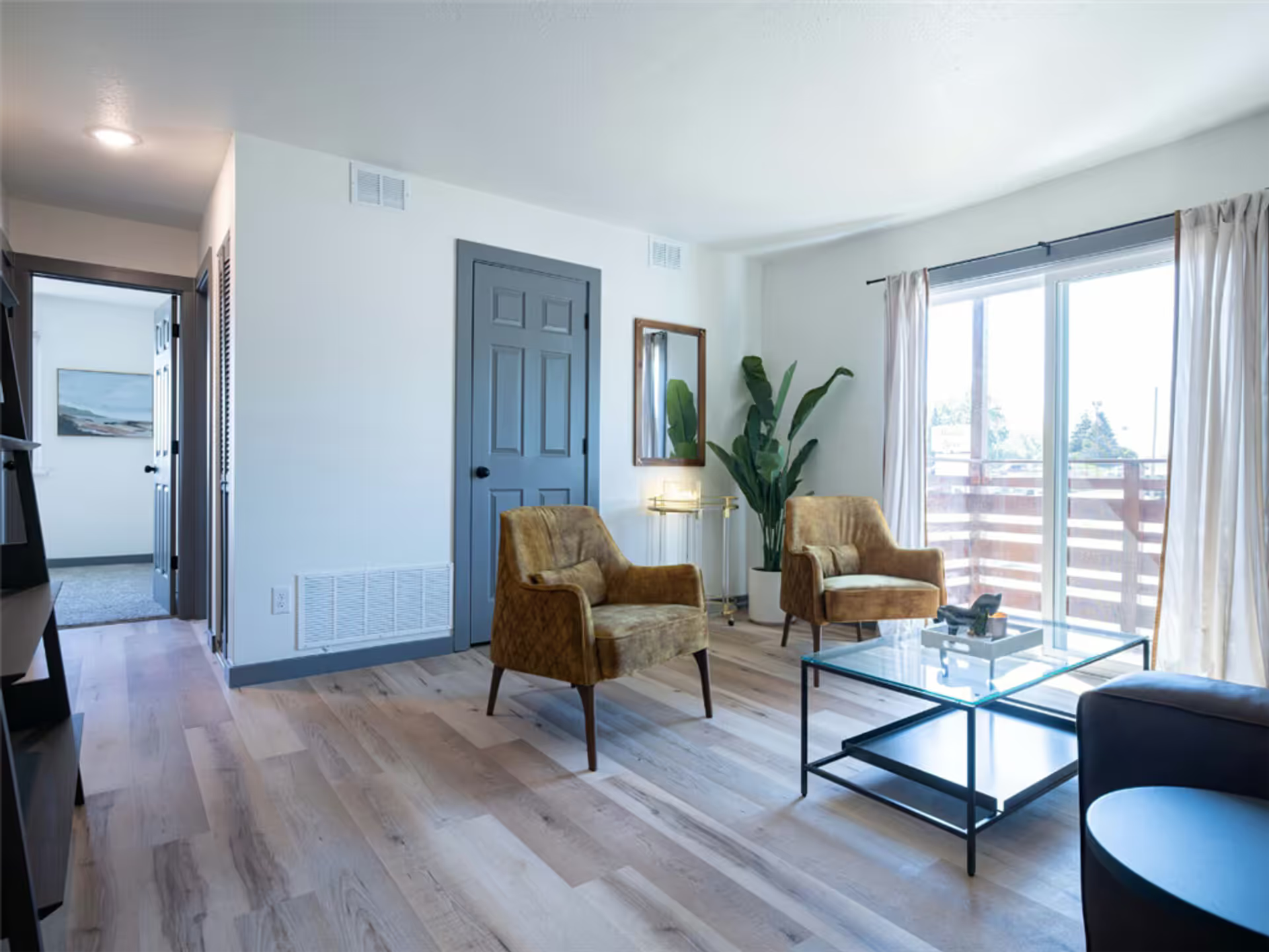 A living room with two chairs , a coffee table , and a balcony.