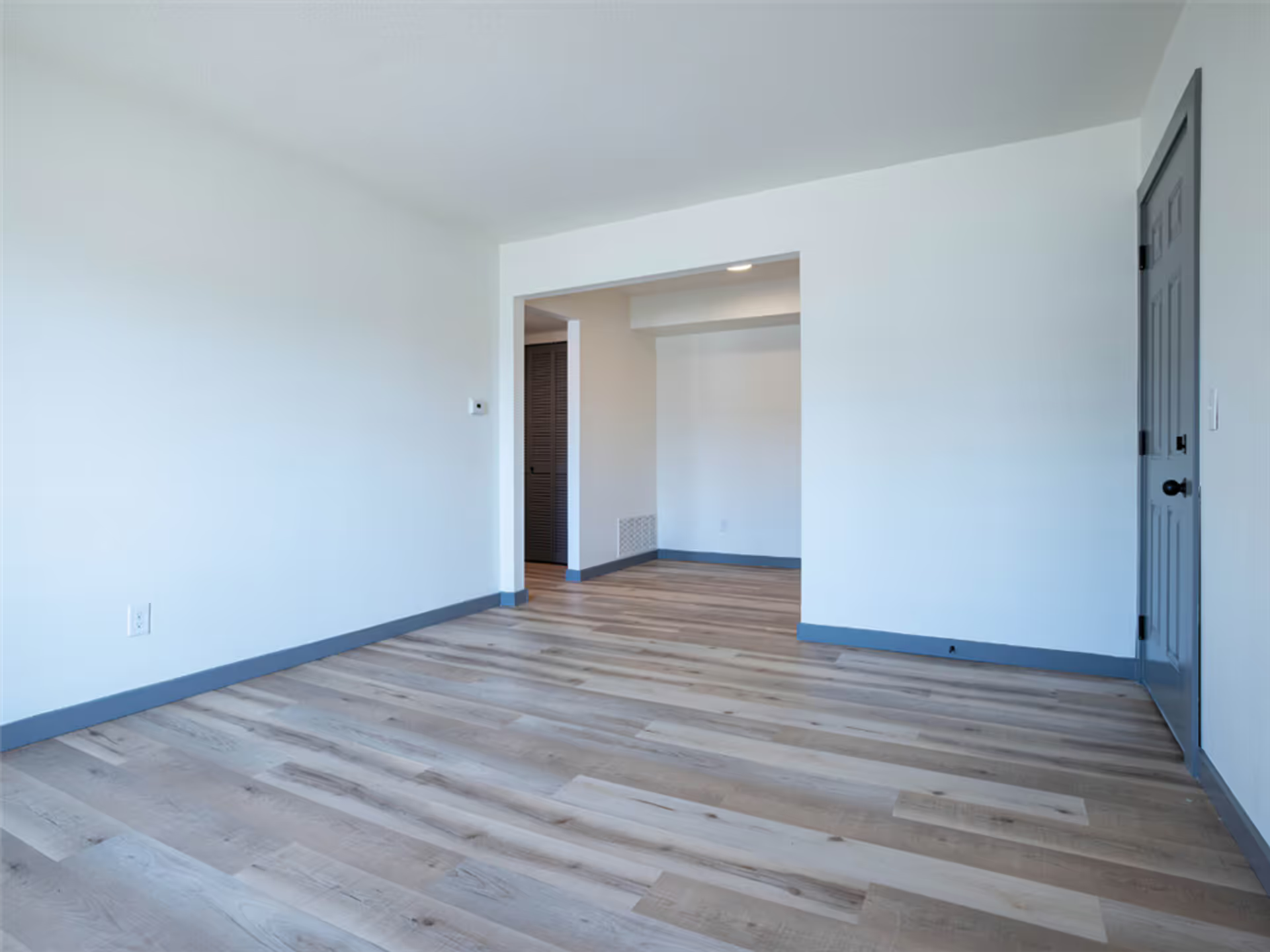 An empty room with hardwood floors and white walls.