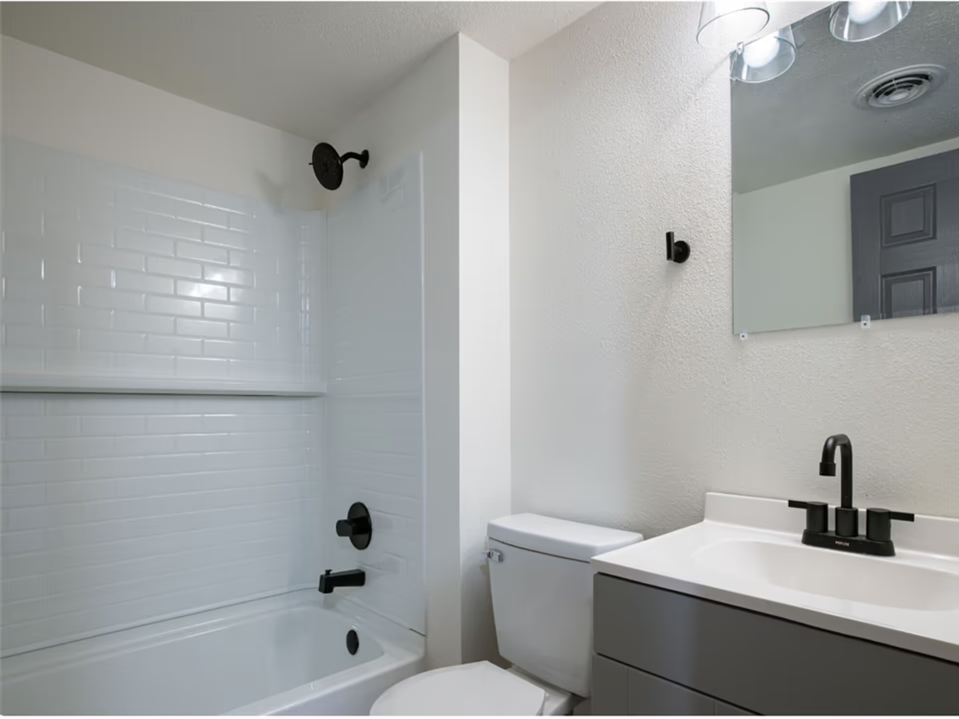 A bathroom with a toilet , sink , bathtub and mirror.