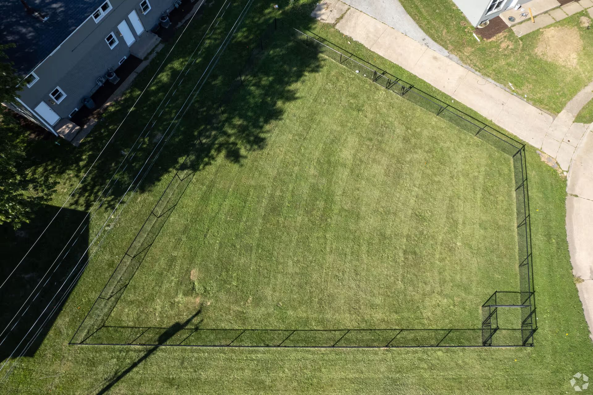 An aerial view of a fenced in yard with a house in the background.