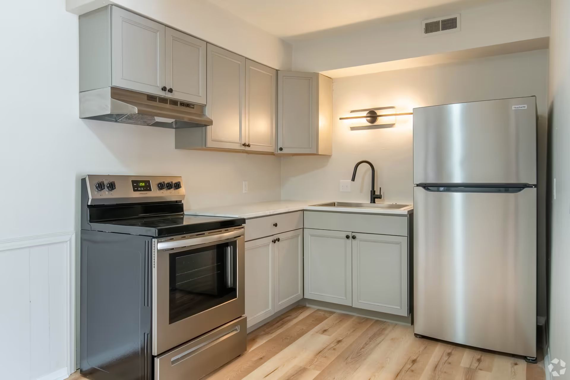 A kitchen with a stove , refrigerator , sink and cabinets.