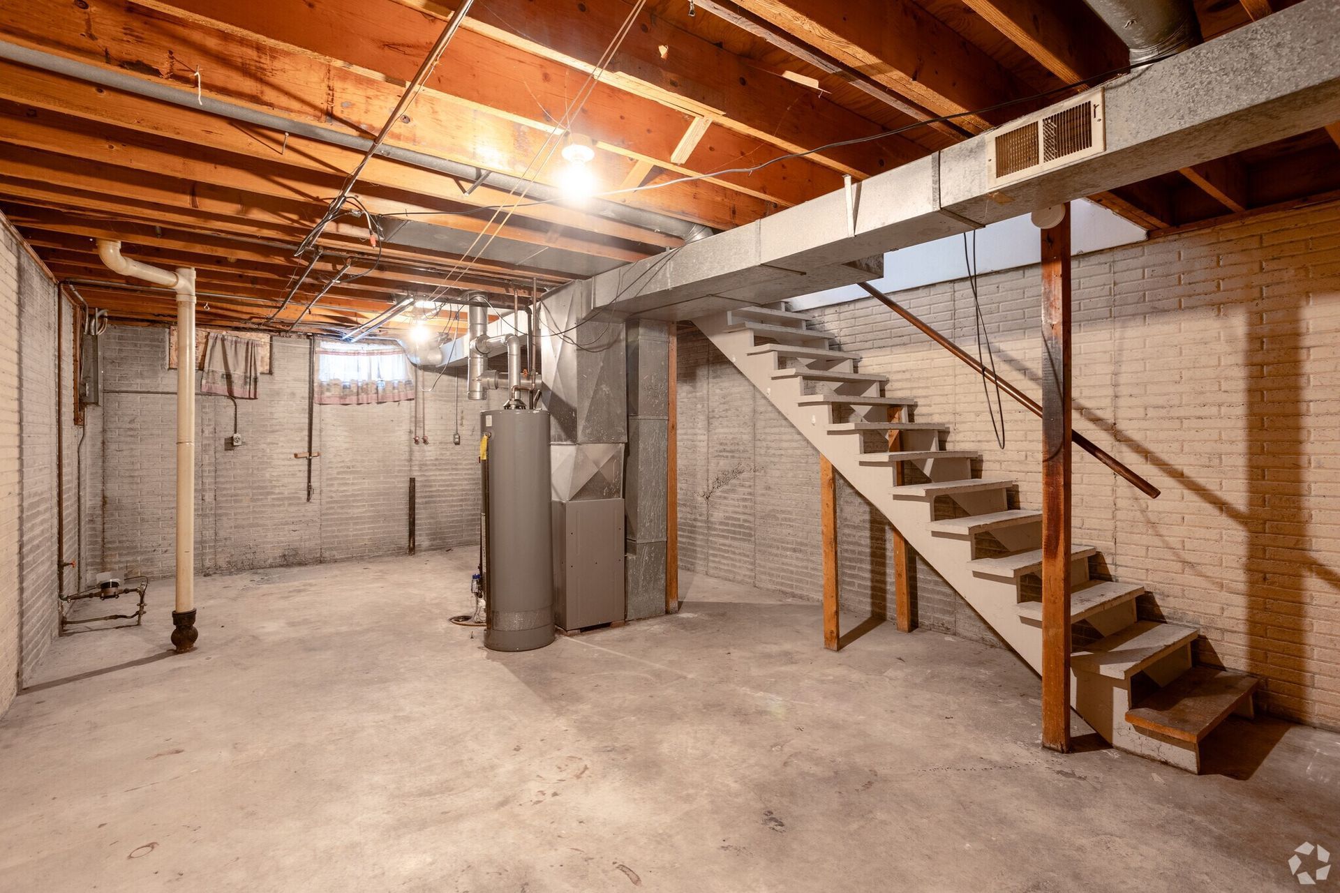 An empty basement with stairs leading up to the second floor.