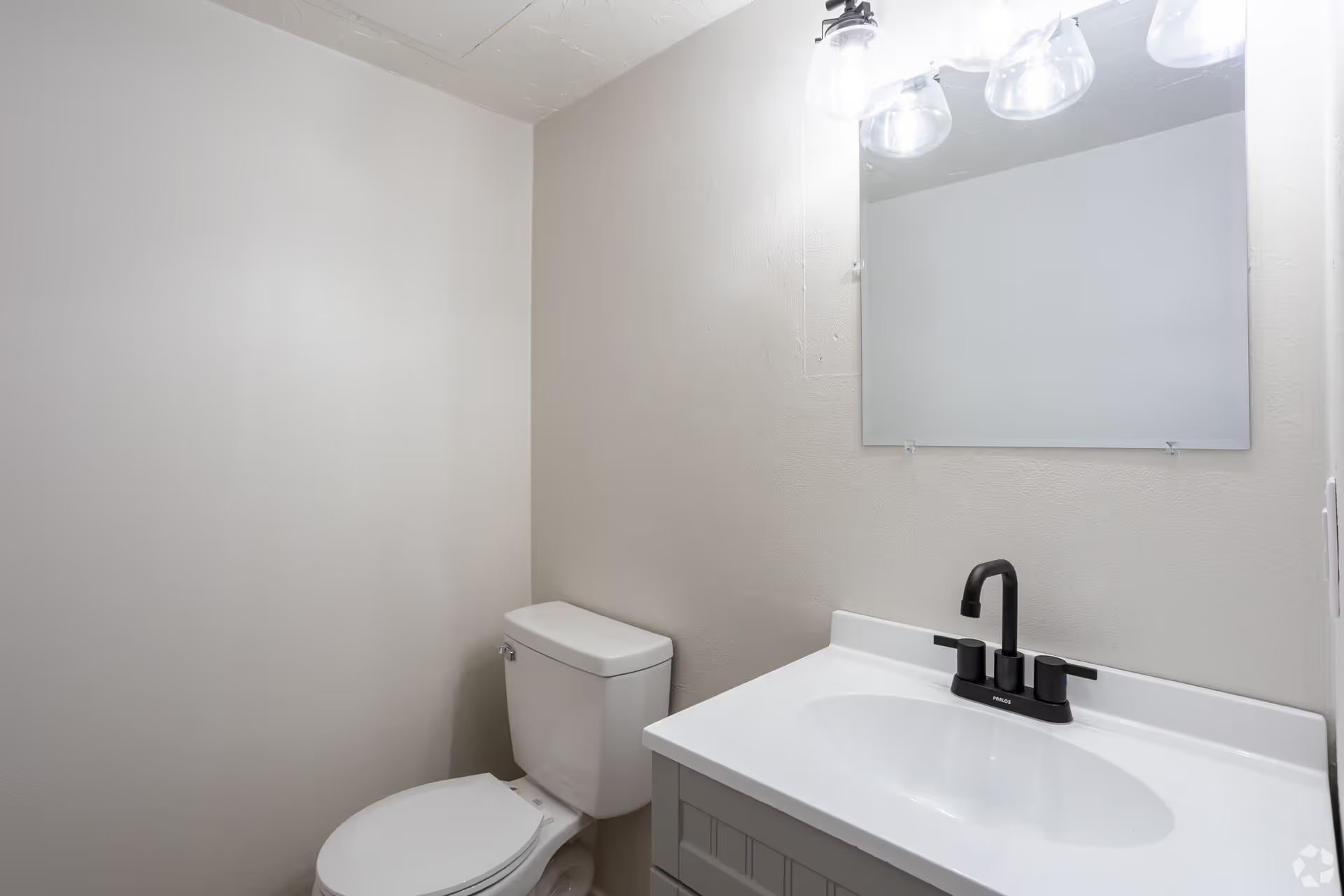 A bathroom with a toilet , sink and mirror.